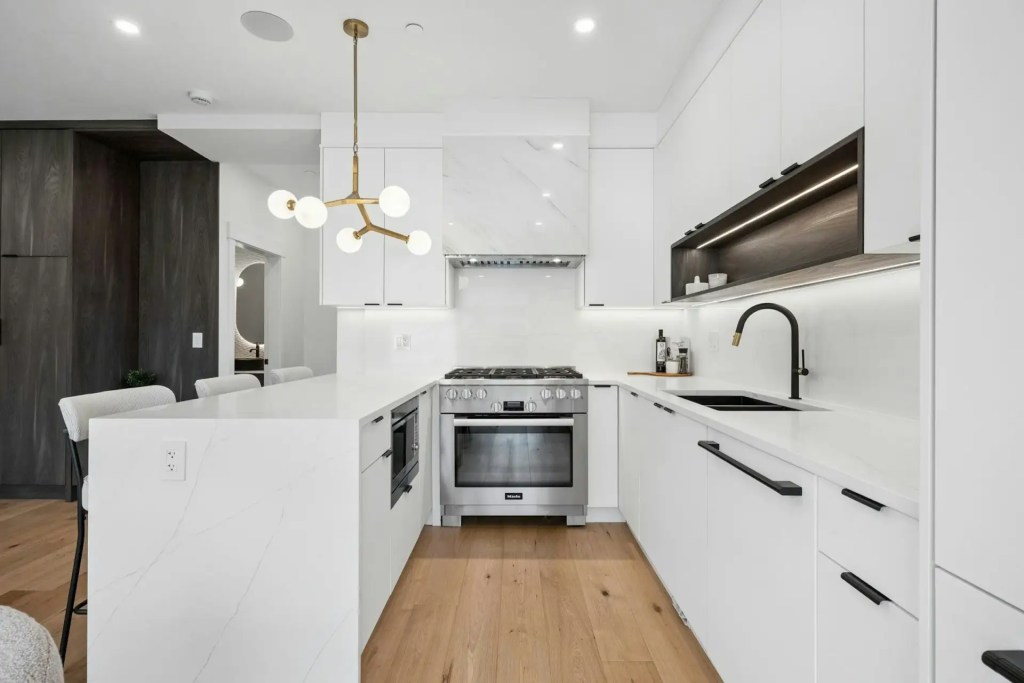 Modern white kitchen renovation with quartz countertops, black fixtures and wood flooring in Point Grey, Dunbar, or Kitsilano, Vancouver
