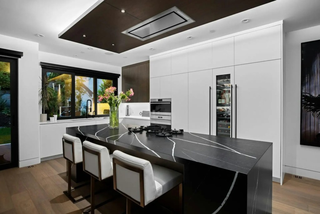 Modern luxury kitchen renovation with white cabinetry, a black waterfall island, integrated appliances and hardwood flooring in Point Grey, Dunbar, or Kitsilano, Vancouver
