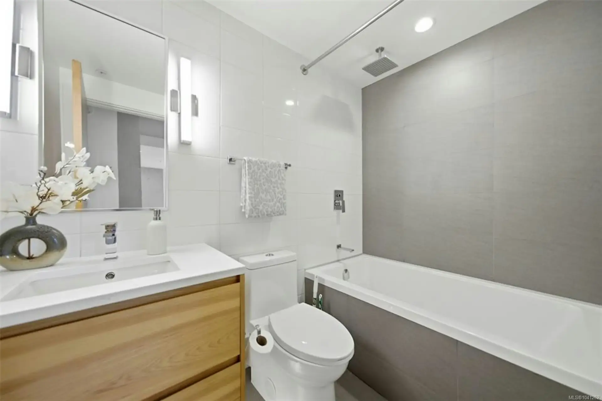 Modern bathroom renovation in Victoria, BC with a wood vanity, bathtub and glass shower screen