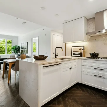 Modern white kitchen renovation with quartz countertops, island and hardwood flooring in Vancouver.